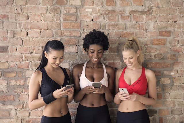 kulturell diverse Gruppe von Frauen blickt auf ihr Smartphone nach dem Workout gesundheittanken.de Sidebar